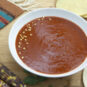 white-bowl-of-New-Mexican-style-red-chile-sauce-garnished-with-seeds-and-tortillas