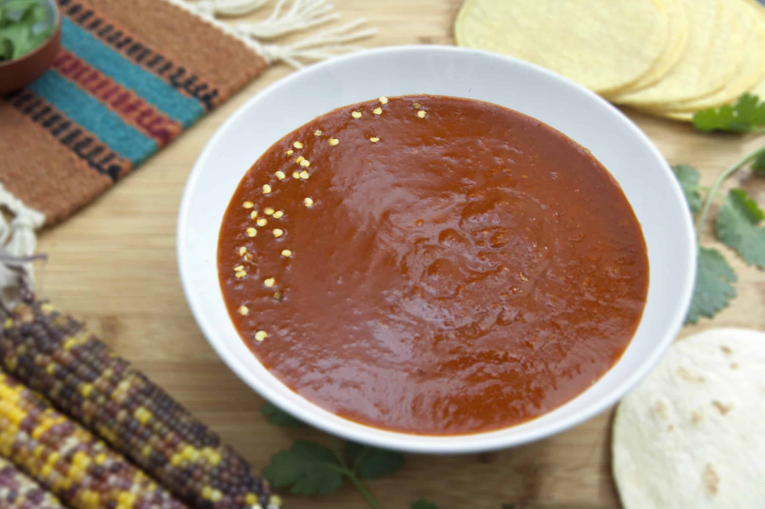 white-bowl-of-New-Mexican-style-red-chile-sauce-garnished-with-seeds-and-tortillas