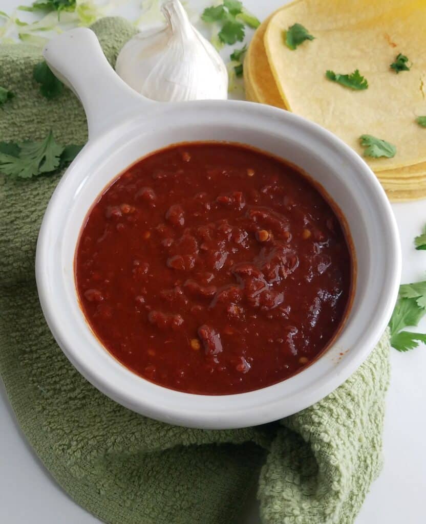 white-bowl-of-New-Mexican-Style-Red-Chile-Sauce-with-tortillas-garlic-and-cilantro