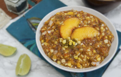 round-white-bowl-filled-with-Colorado-salsa-Palisade-peaches-Pueblo-green-chiles-and-olathe-sweet-corn-garnished-with-lime