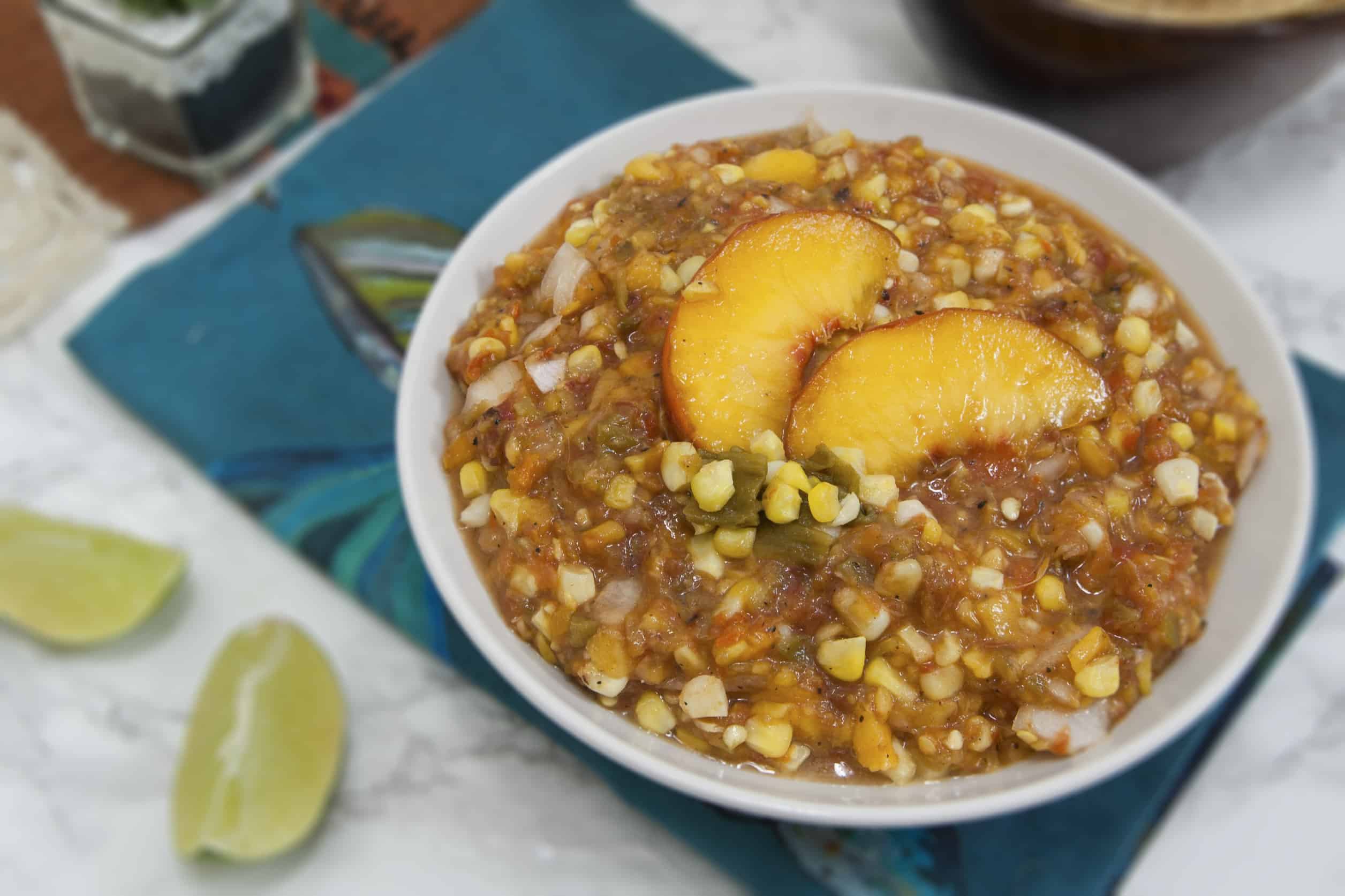 round-white-bowl-filled-with-Colorado-salsa-Palisade-peaches-Pueblo-green-chiles-and-olathe-sweet-corn-garnished-with-lime