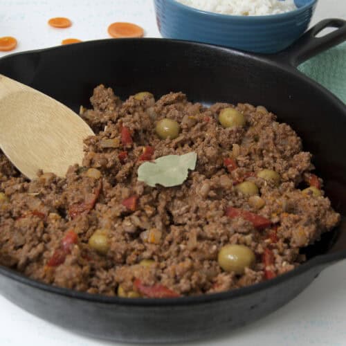 Cast-iron-pan-of-Cuban-picadillo-with-wooden-spoon-and-bay-leaf