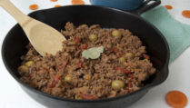 Cast-iron-pan-of-Cuban-picadillo-with-wooden-spoon-and-bay-leaf