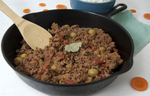 Cast-iron-pan-of-Cuban-picadillo-with-wooden-spoon-and-bay-leaf