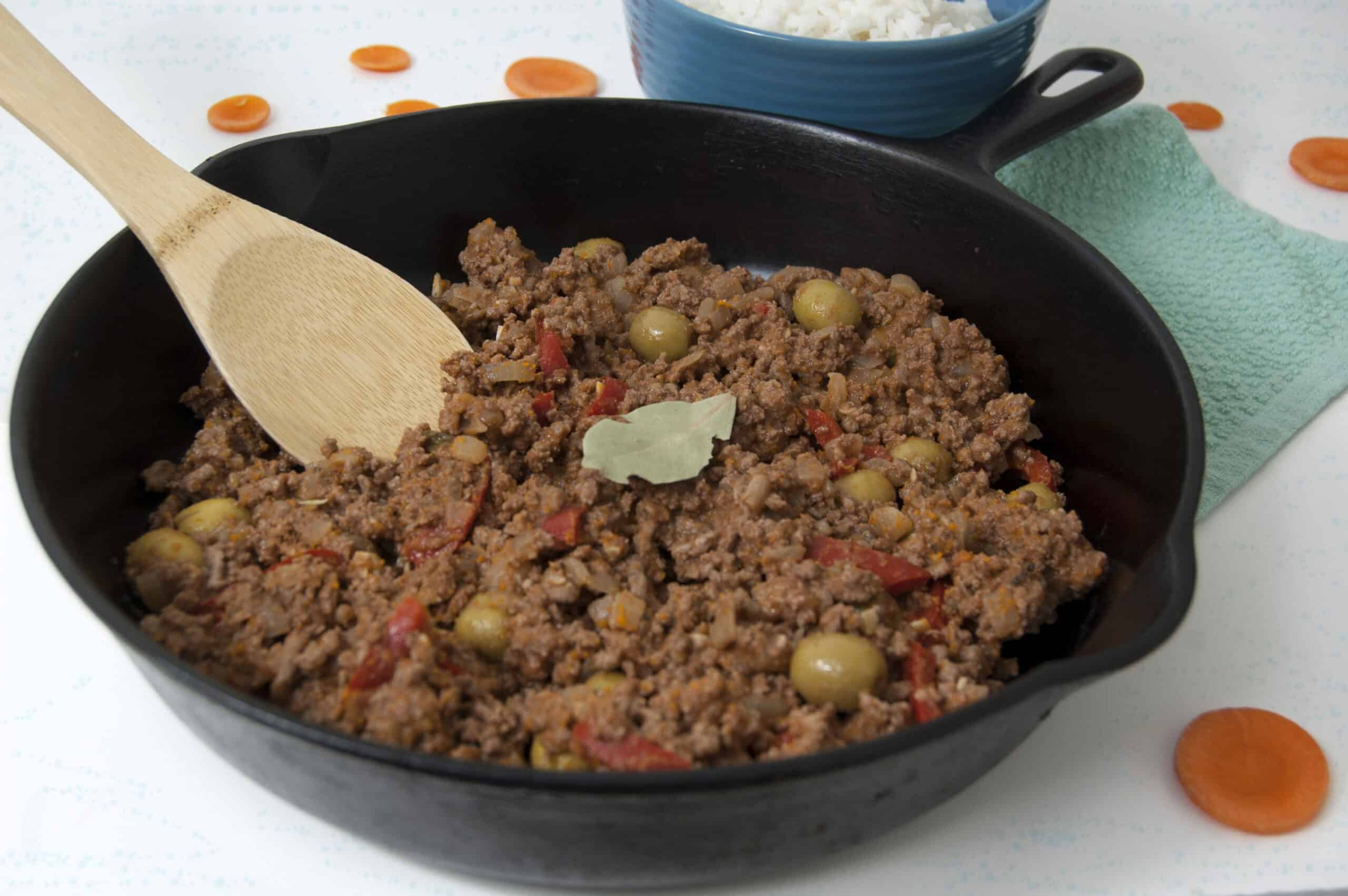 Cast-iron-pan-of-Cuban-picadillo-with-wooden-spoon-and-bay-leaf