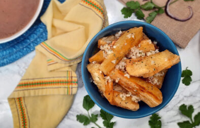 Yuca-frita-con-mojo-offcenter-in-blue-bowl-with-yellow-napkin-and-garnish