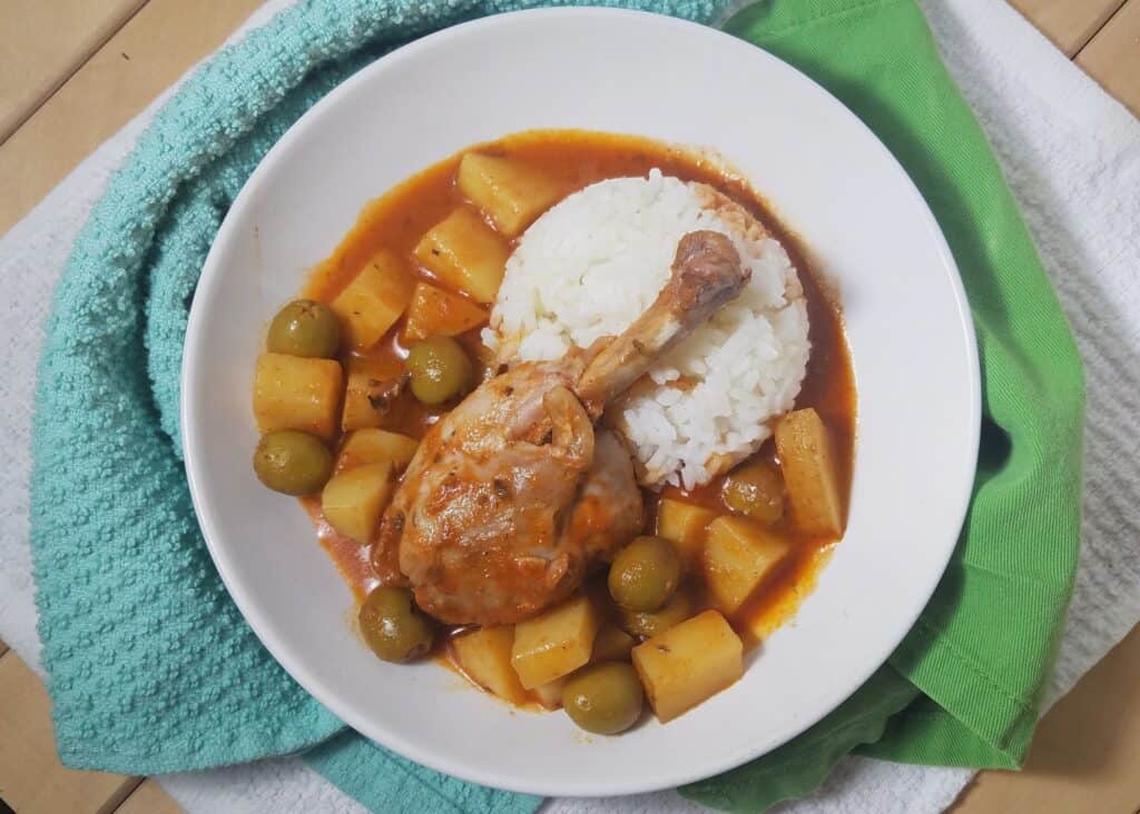 Cuban-fricase-de-pollo-single-drumstick-served-over-rice-in-white-bowl