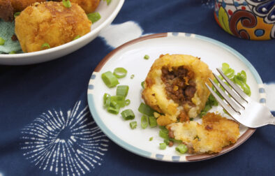 top-view-Cuban-Papas-Rellenas-broken-open-with-fork-and-green-onions