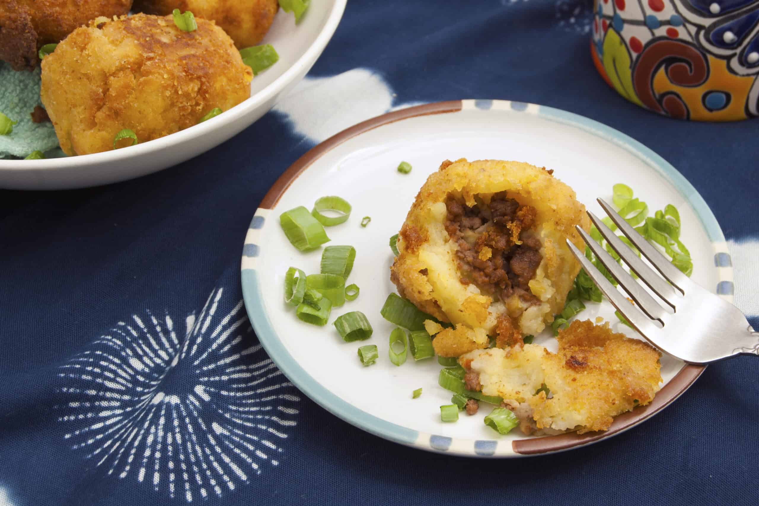 top-view-Cuban-Papas-Rellenas-broken-open-with-fork-and-green-onions