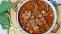 pot-of-Cuban-Fricasé-de-pollo-with-four-drumsticks-potatoes-olives-on-yellow-background