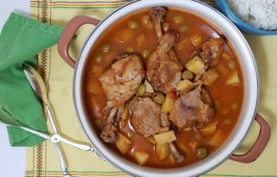 pot-of-Cuban-Fricasé-de-pollo-with-four-drumsticks-potatoes-olives-on-yellow-background