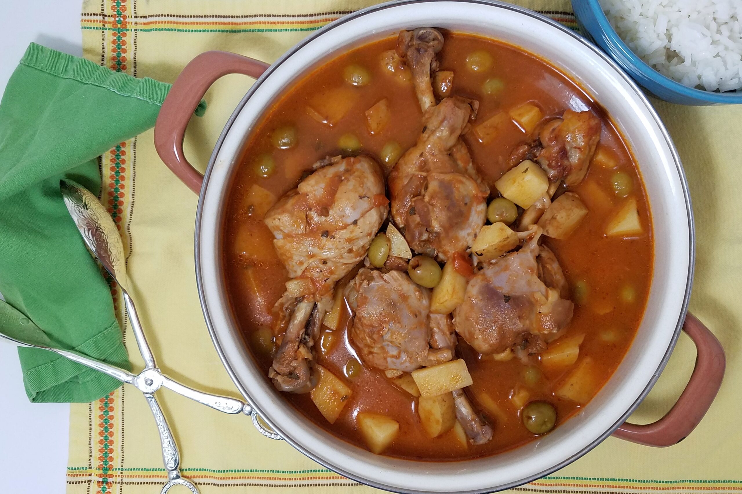 pot-of-Cuban-Fricasé-de-pollo-with-four-drumsticks-potatoes-olives-on-yellow-background