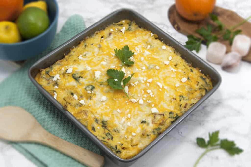 side-view-baked-breakfast-polenta-in-silver-baking-dish-next-to-bowl-of-fruit