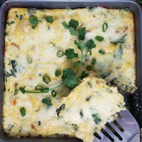 one-serving-breakfast-polenta-casserole-cut-from-baking-dish-with-spatula-on-wooden-board