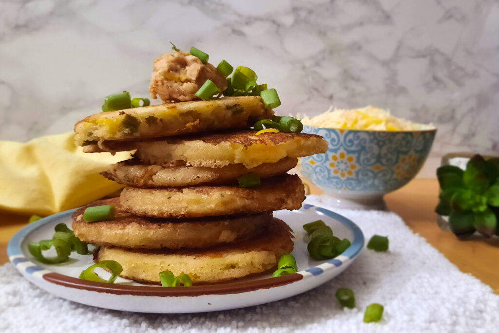 side-view-stacked-cheddar-scallion-sourdough-pancakes-topped-with-miso-butter-and-green-onions