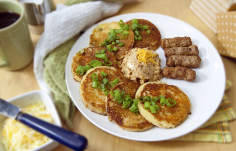 six-cheddar-scallion-sourdough-pancakes-with-miso-butter-arranged-in-semi-circle-served-with-sausage