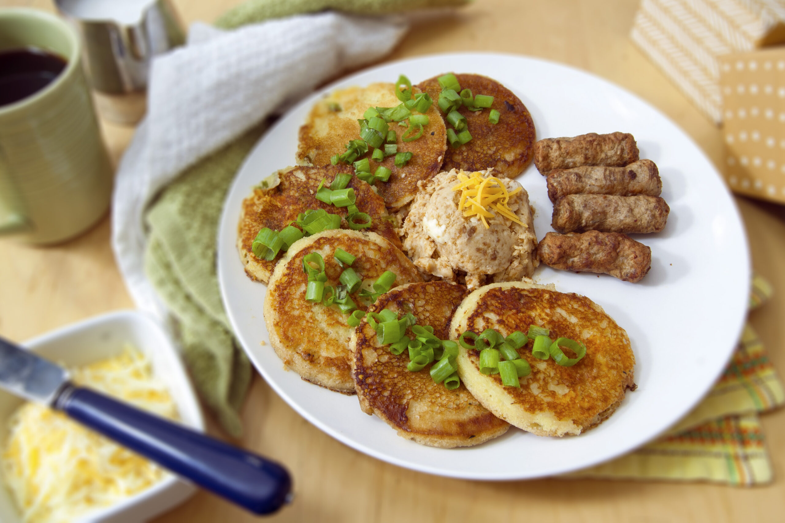 six-cheddar-scallion-sourdough-pancakes-with-miso-butter-arranged-in-semi-circle-served-with-sausage