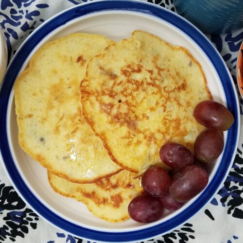 top-view-three-potato-pancakes-on-blue-and-white-plate-served-with-grapes