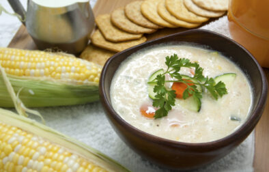 sweet-corn-zucchini-soup-in-brown-wooden-bowl-with-crackers-and-parsley