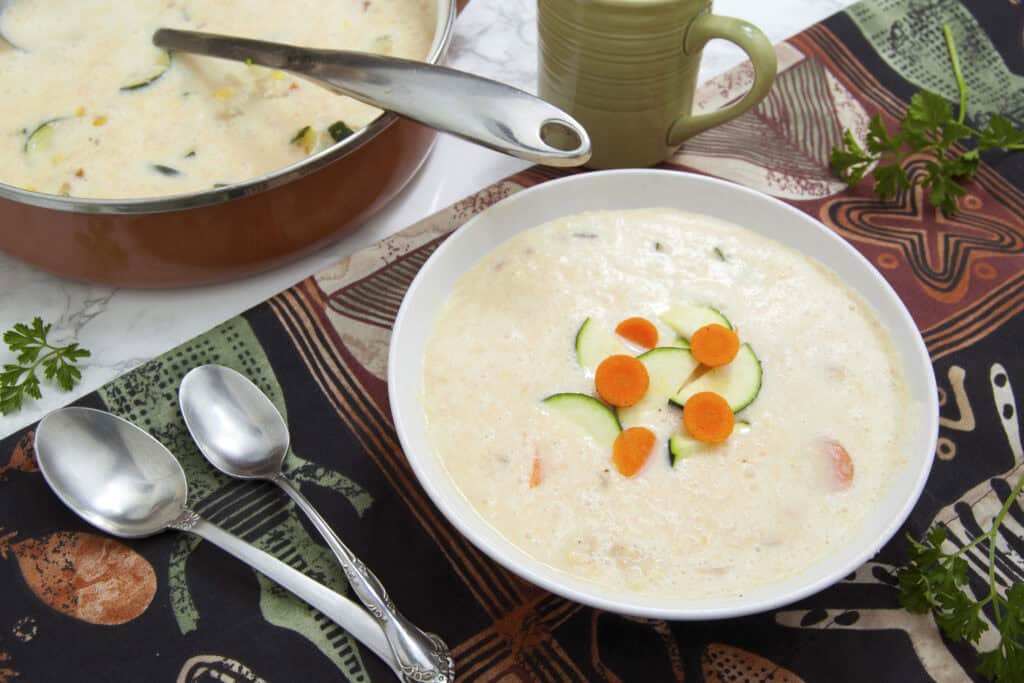 sweet-corn-zucchini-soup-single-serving-in-white-bowl-next-to-brown-pot