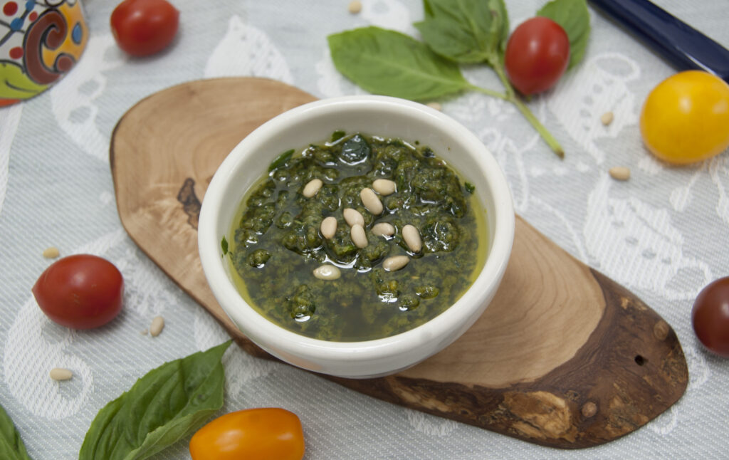 leftover-kaffir-lime-basil-pesto-in-white-bowl-garnished-with-pine-nuts-on-wooden-placemat