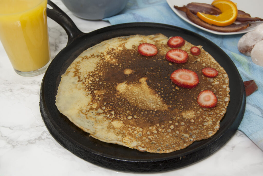 flat-black-castiron-pan-with-single-Swedish-pancake-garnished-with-strawberries