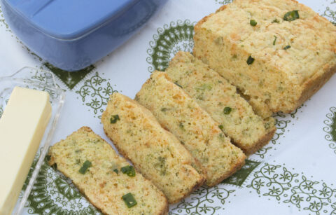 cascading-slices-broccoli-cheddar-bread-on-white-green-paisley-tablecloth-garnished-with-green-onions