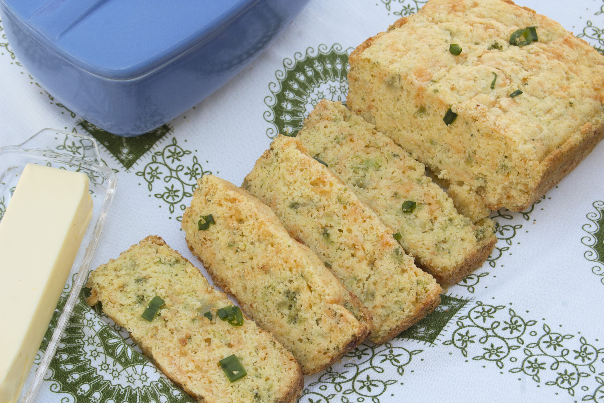 cascading-slices-broccoli-cheddar-bread-on-white-green-paisley-tablecloth-garnished-with-green-onions