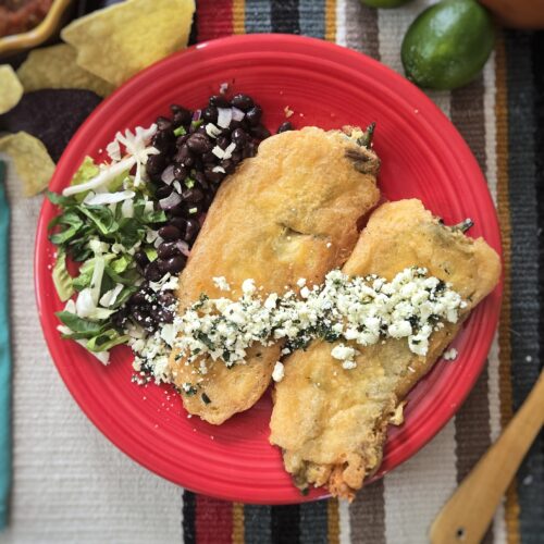 two-Hatch-chiles-rellenos-served-with-black-beans-shredded-lettuce-and-cotija-cheese