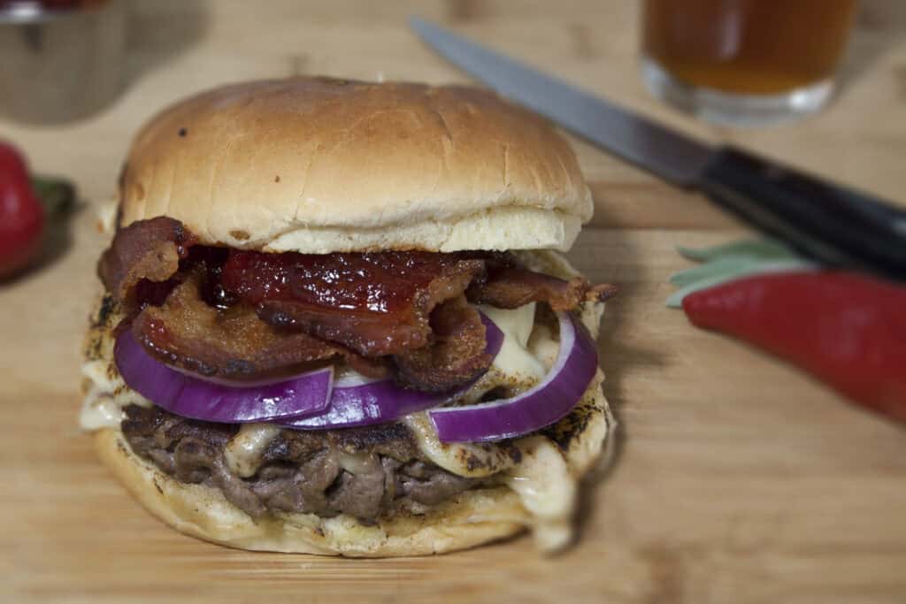 side-view-of-Jelly-Biafra-smashburger-with-crispy-bacon-havarti-red-onions-and-red-pepper-jelly