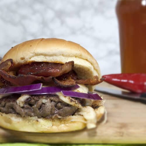 smash-burger-with-Havarti-red-onions-and-red-pepper-jelly-served-on-cutting-board-with-beer