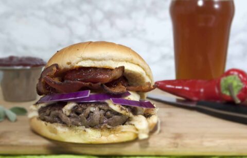 smash-burger-with-Havarti-red-onions-and-red-pepper-jelly-served-on-cutting-board-with-beer