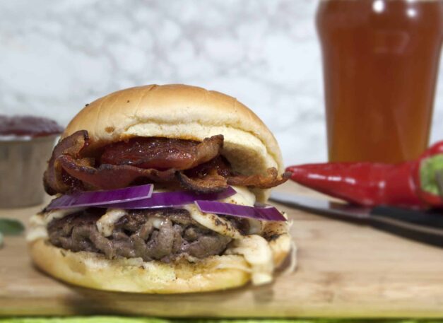 smash-burger-with-Havarti-red-onions-and-red-pepper-jelly-served-on-cutting-board-with-beer